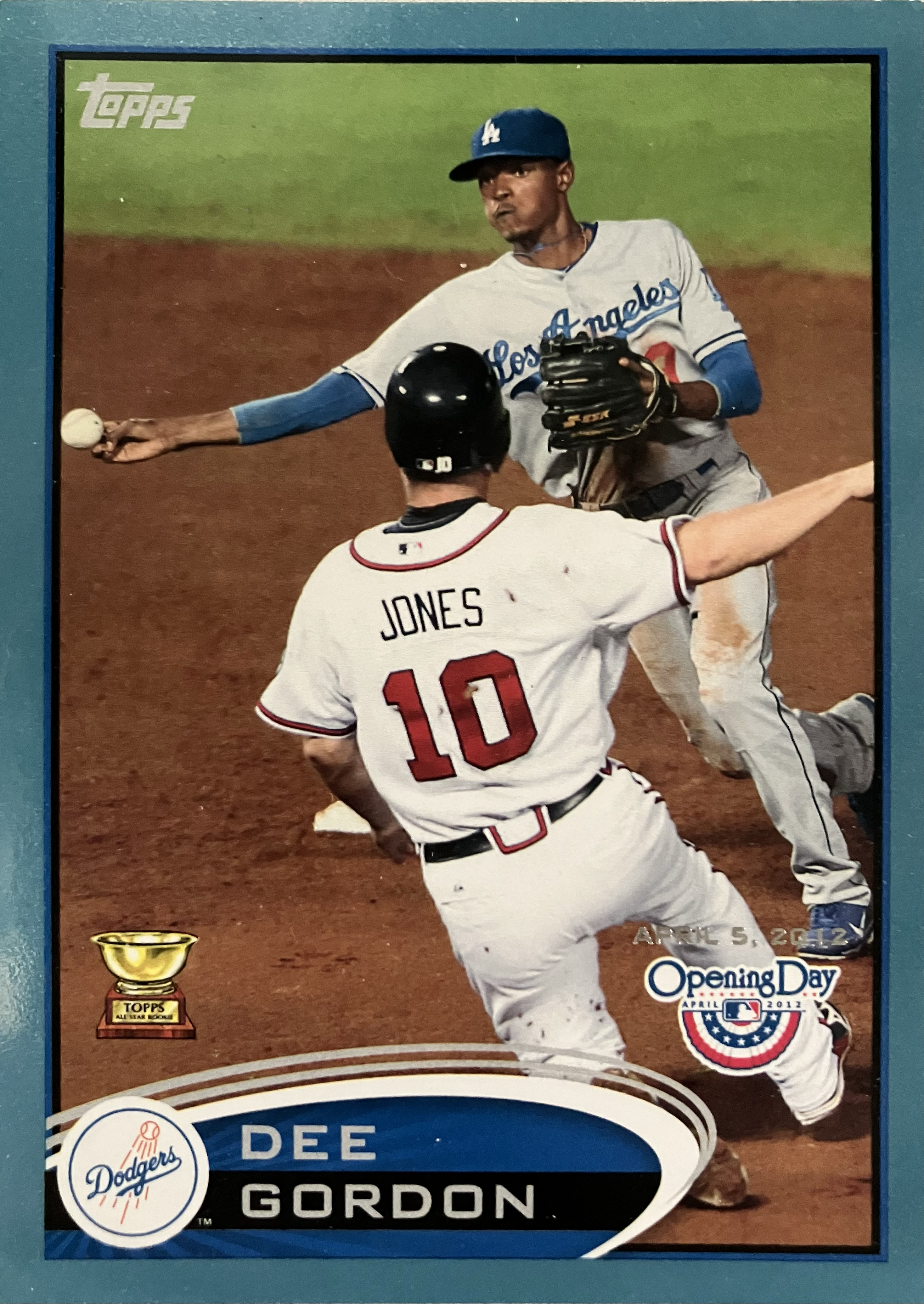 A baseball player throws the ball side armed while a runner slides into second base.
