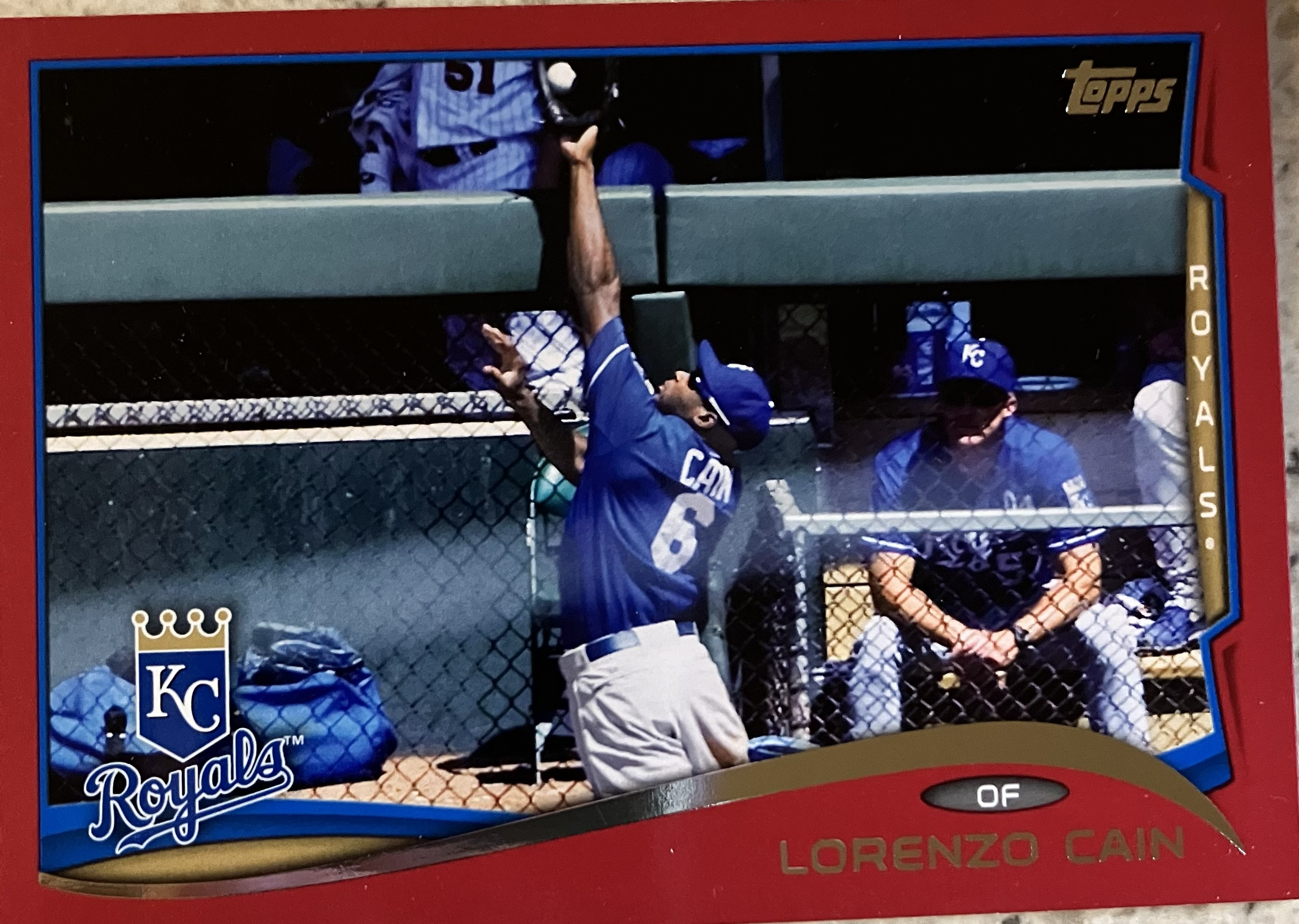 A baseball player jumping to catch a ball about to go over a wall.
