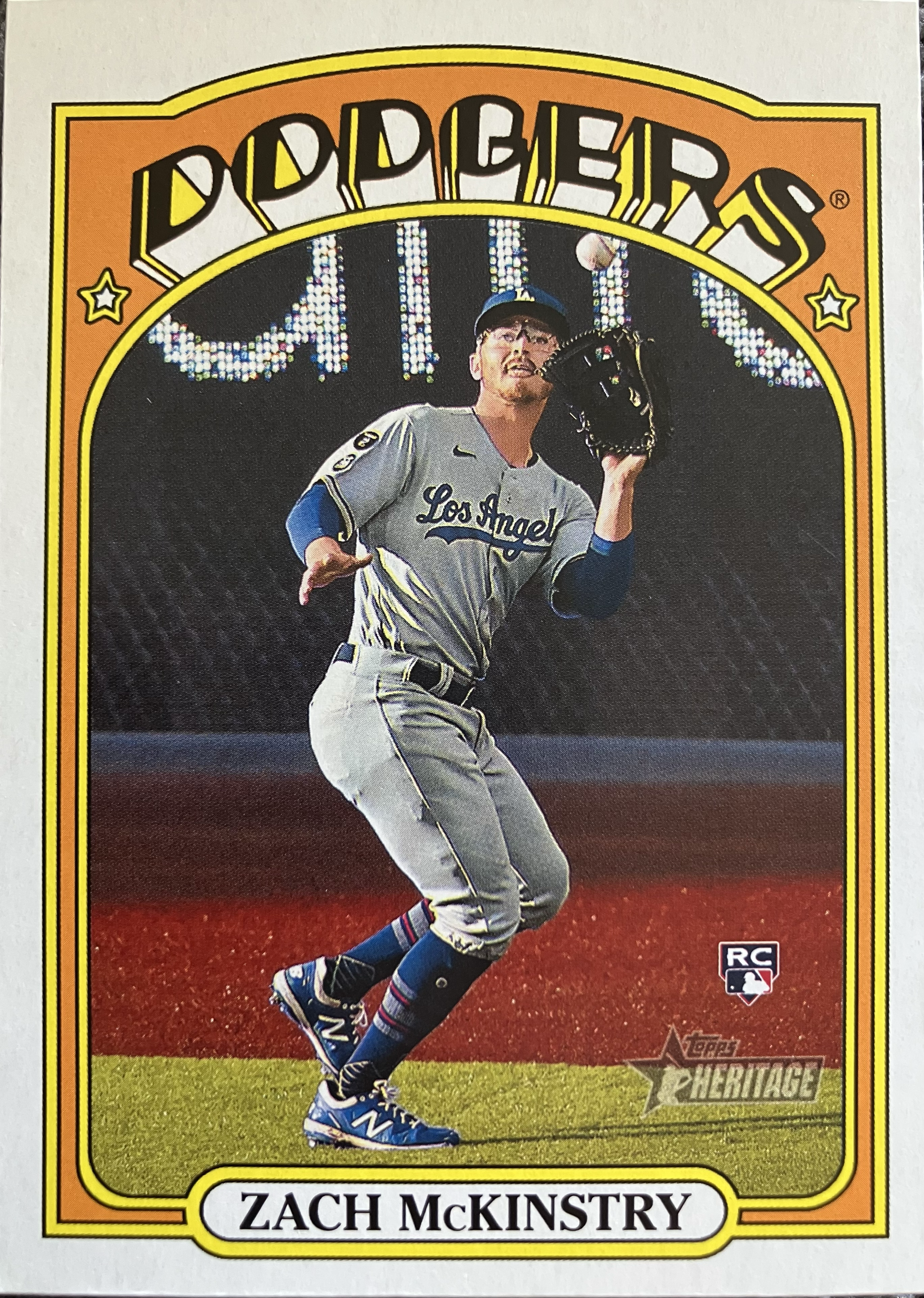 A baseball player catching a fly ball, nearly at the warning track.