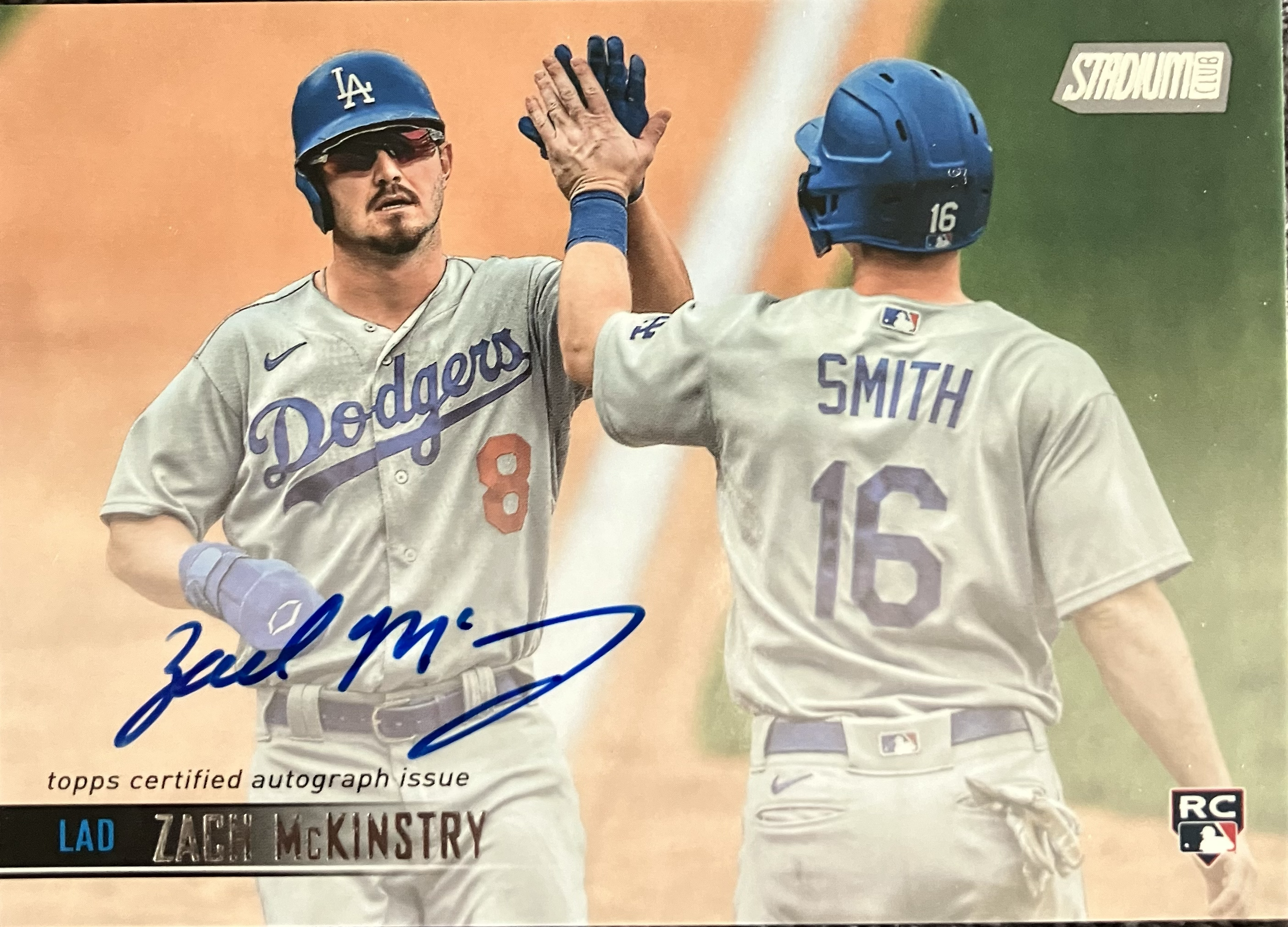 Two baseball players high fiving at home plate after scoring.